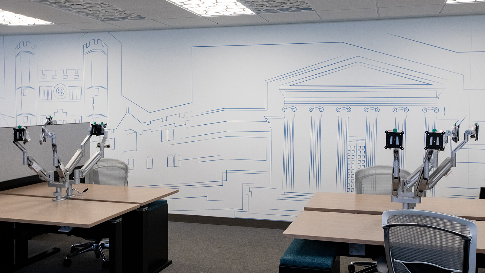 Photo of desks and wall mural depicting sketches of campus buildings