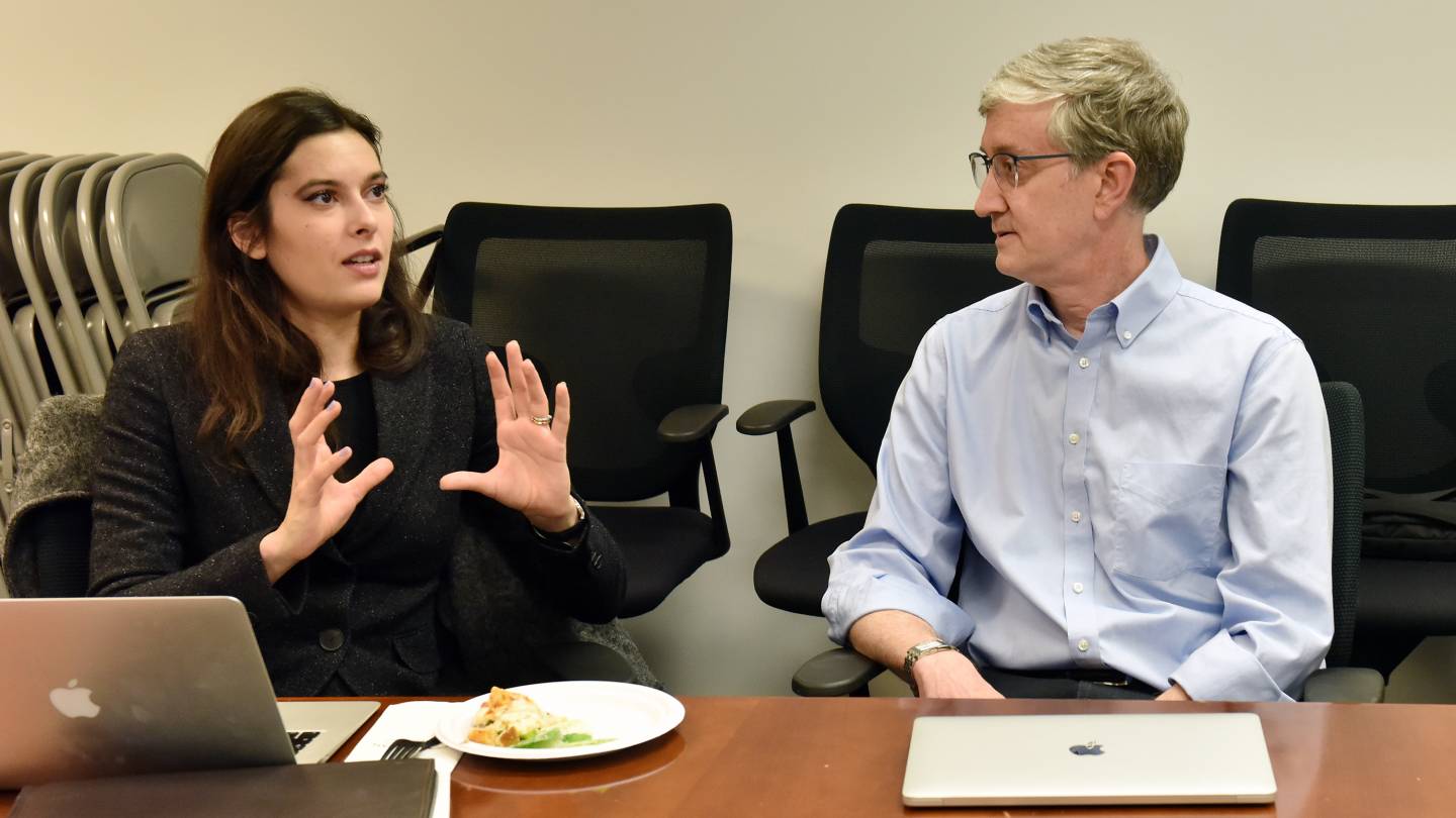 Annette Zimmerman, left, a postdoctoral research associate in values and public policy, and Ed Felten, right, the Robert E. Kahn Professor of Computer Science and Public Affairs and director of the Center for Information Technology Policy, sit at a conference table. She is gesturing.  Photo by Mark Czajkowski