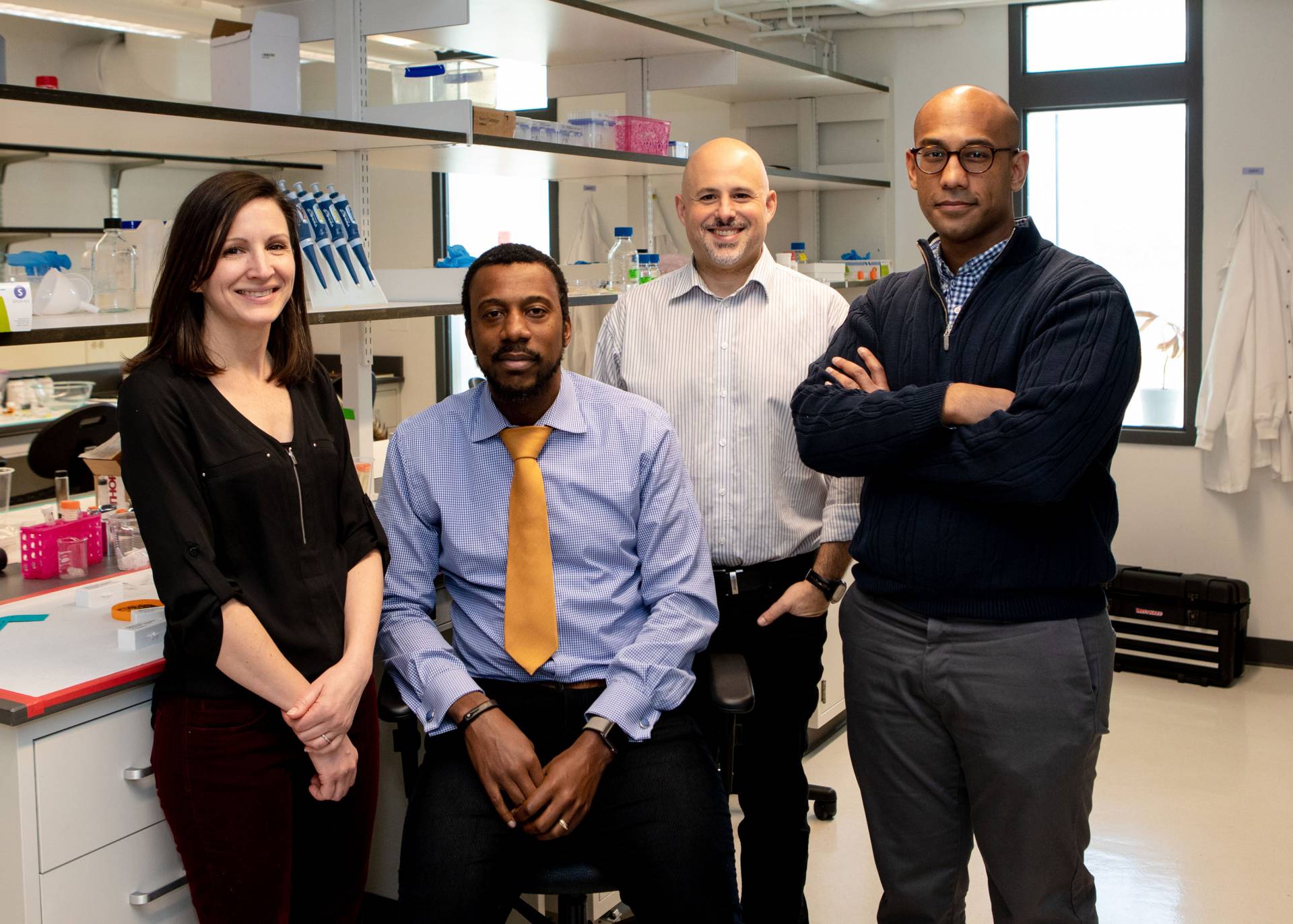 Four researchers pose for photo in lab: Devenport, Priestley, Gitai and Datta.