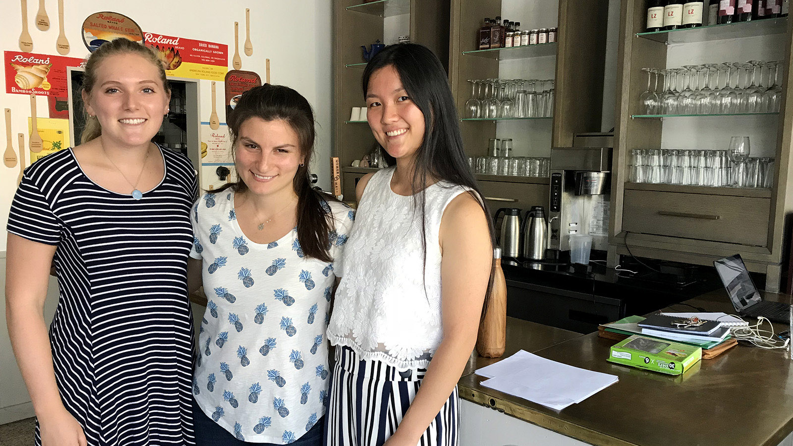Two student interns stand with non-profit founder inside restaurant