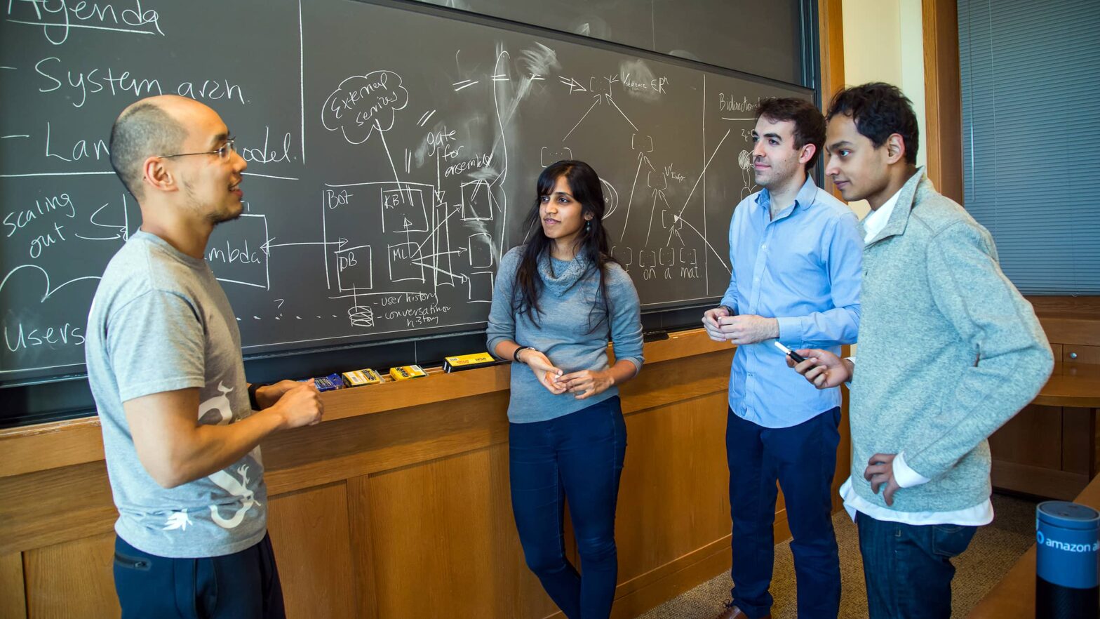 Graduate students discuss their research in front of blackboard