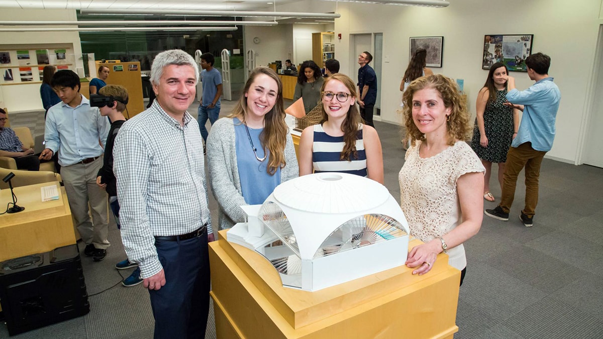 Researchers and student in front of a model building