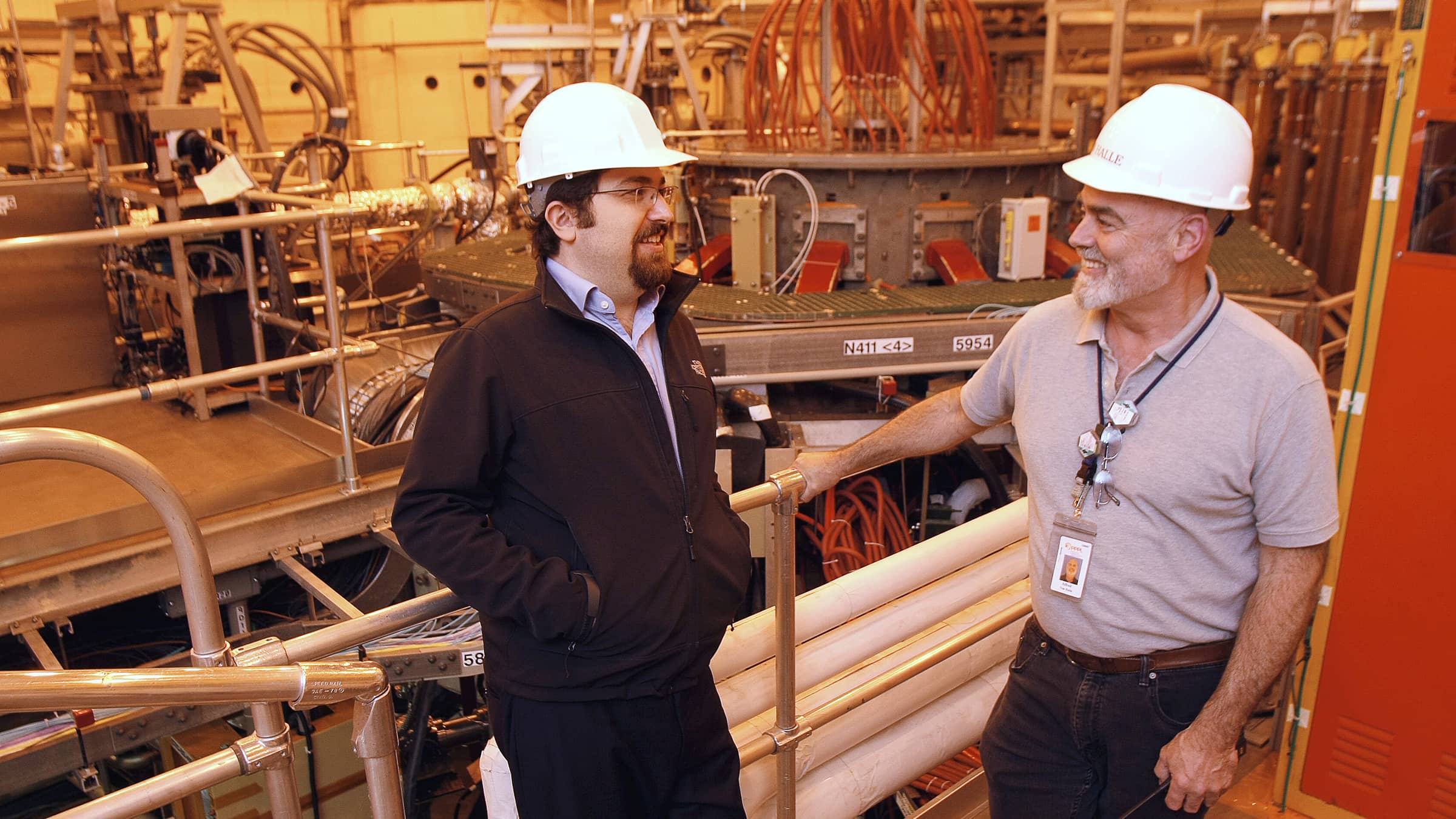 Egeman Koleman speaks with Al von Halle at Princeton Plasma Physics Laboratory. They are wearing hard hats.