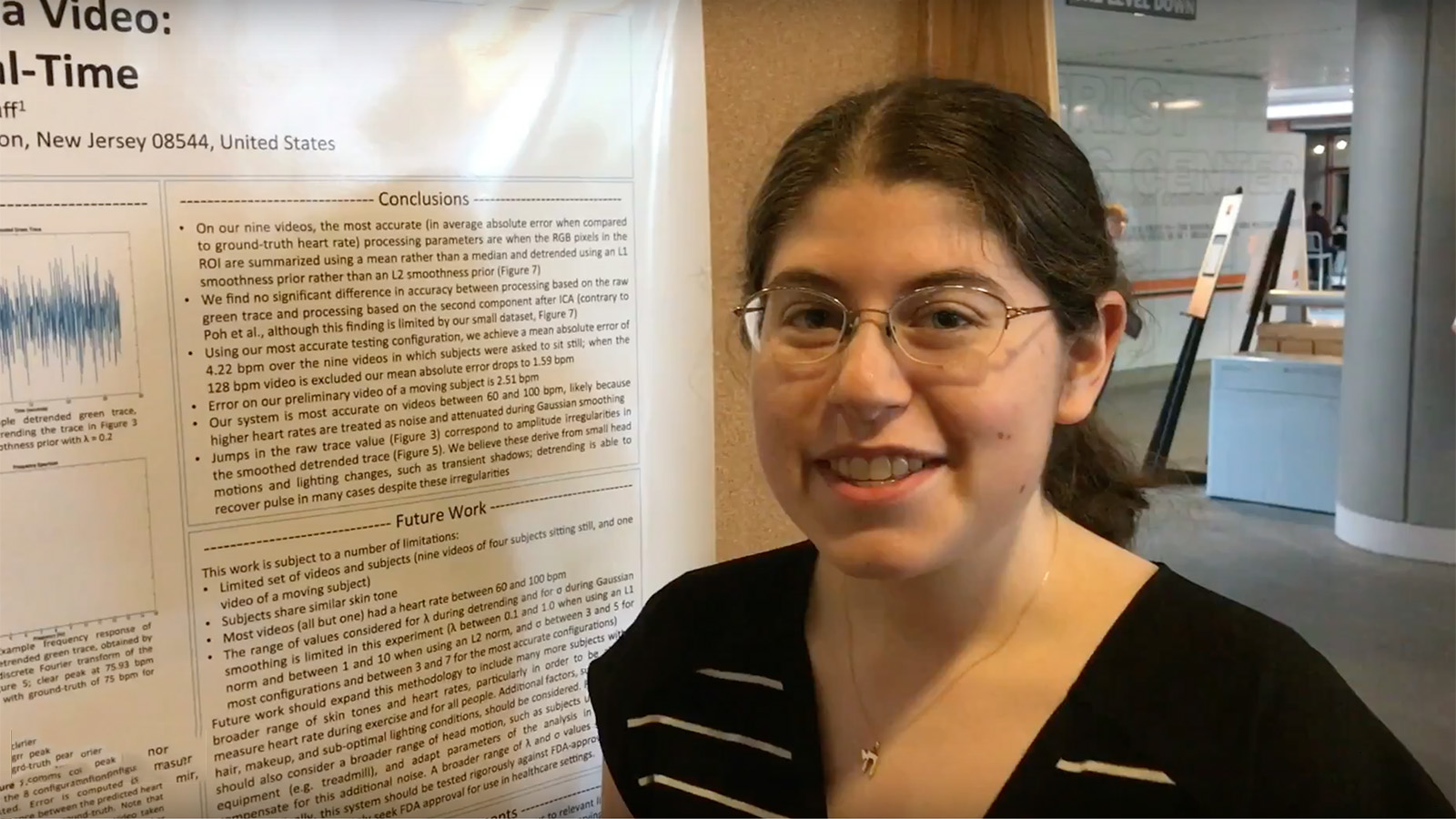 Student speaks in front of research poster