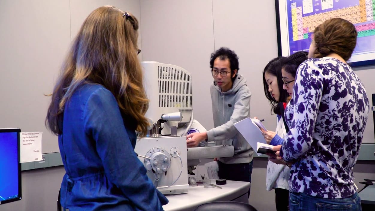Students gather around computer lab equipment