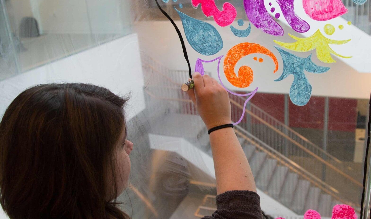 Students drawing on glass wall.