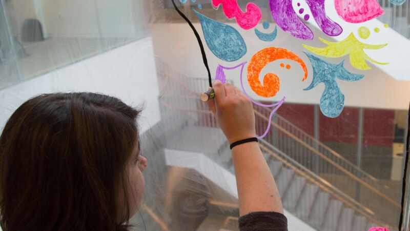 Students drawing on glass wall.