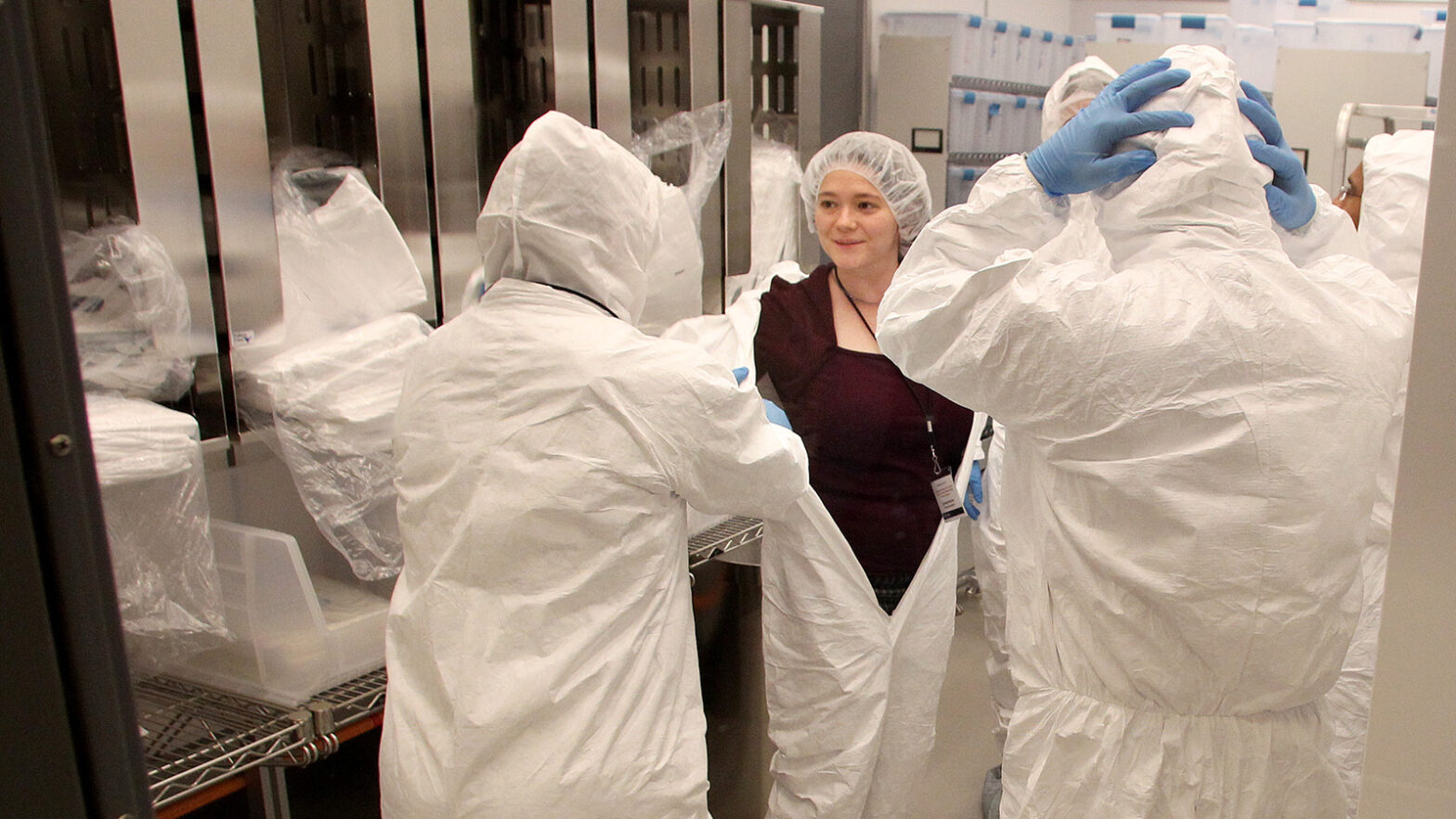 Researchers put on white suits in preparation for entering "clean room" lab