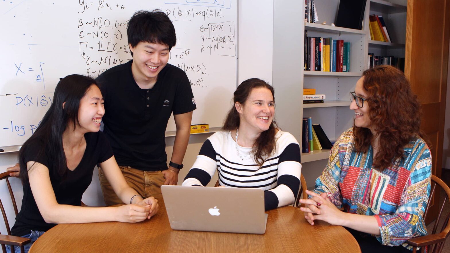 Barbara Engelhardt with students, crowding around computer, with whiteboard as a backdrop.
