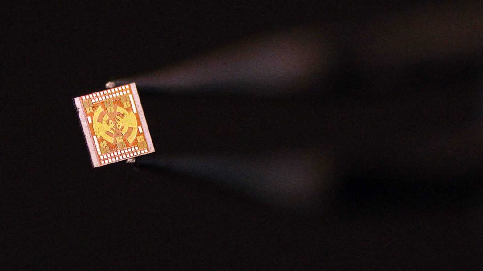 Tiny microchip held by tweezer-like lab equipiment