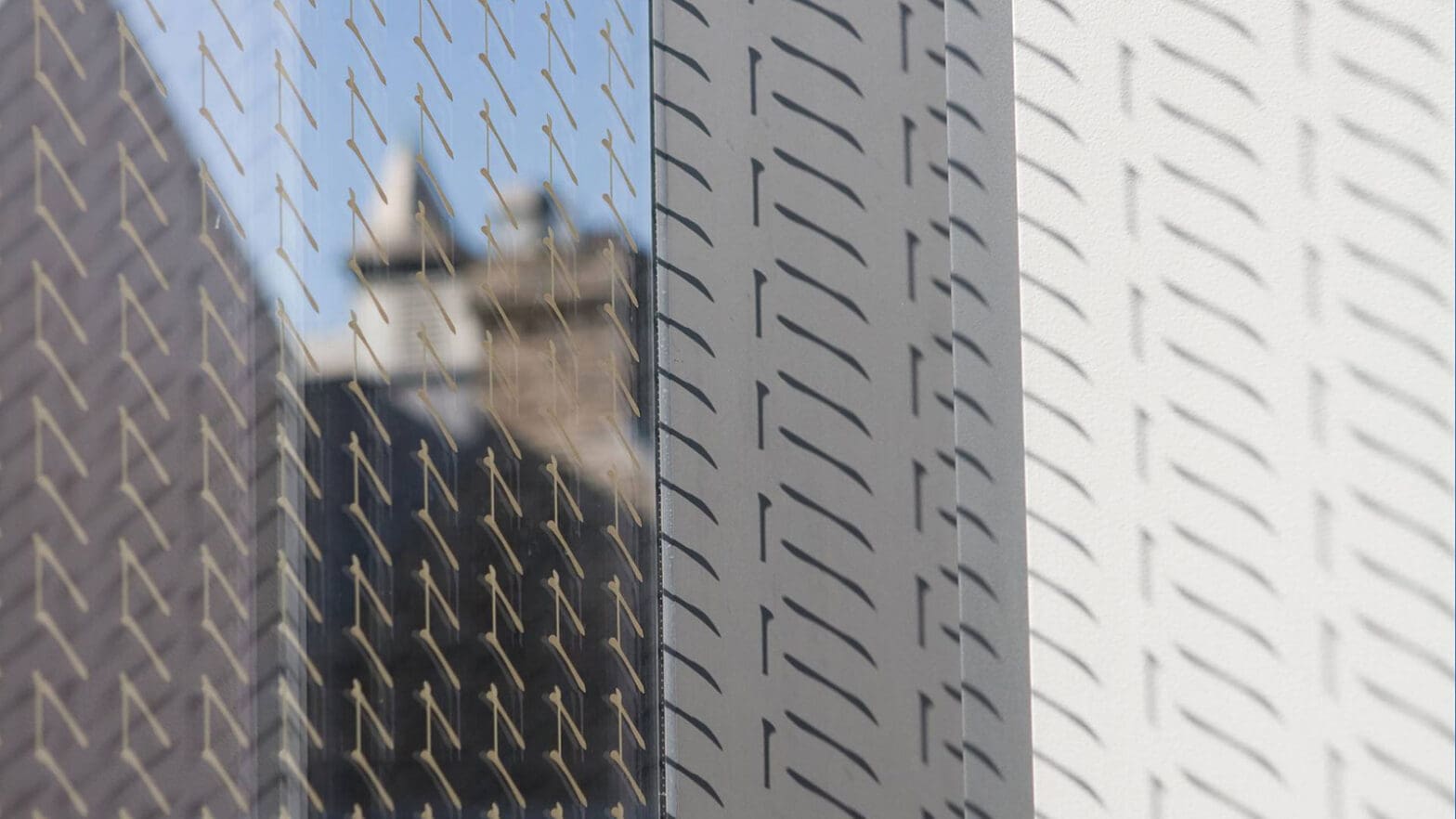 Close-up of "frit" marks in the glass of Sherrerd Hall with reflections of another University building and patterns of light and dark gray