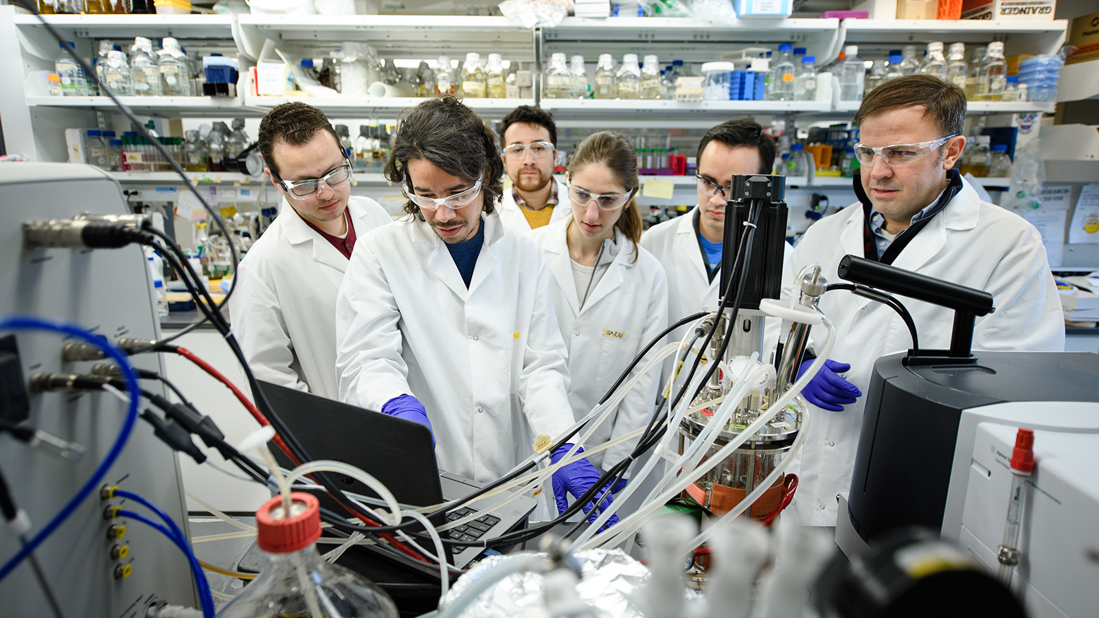 Six researchers look at equipment in lab