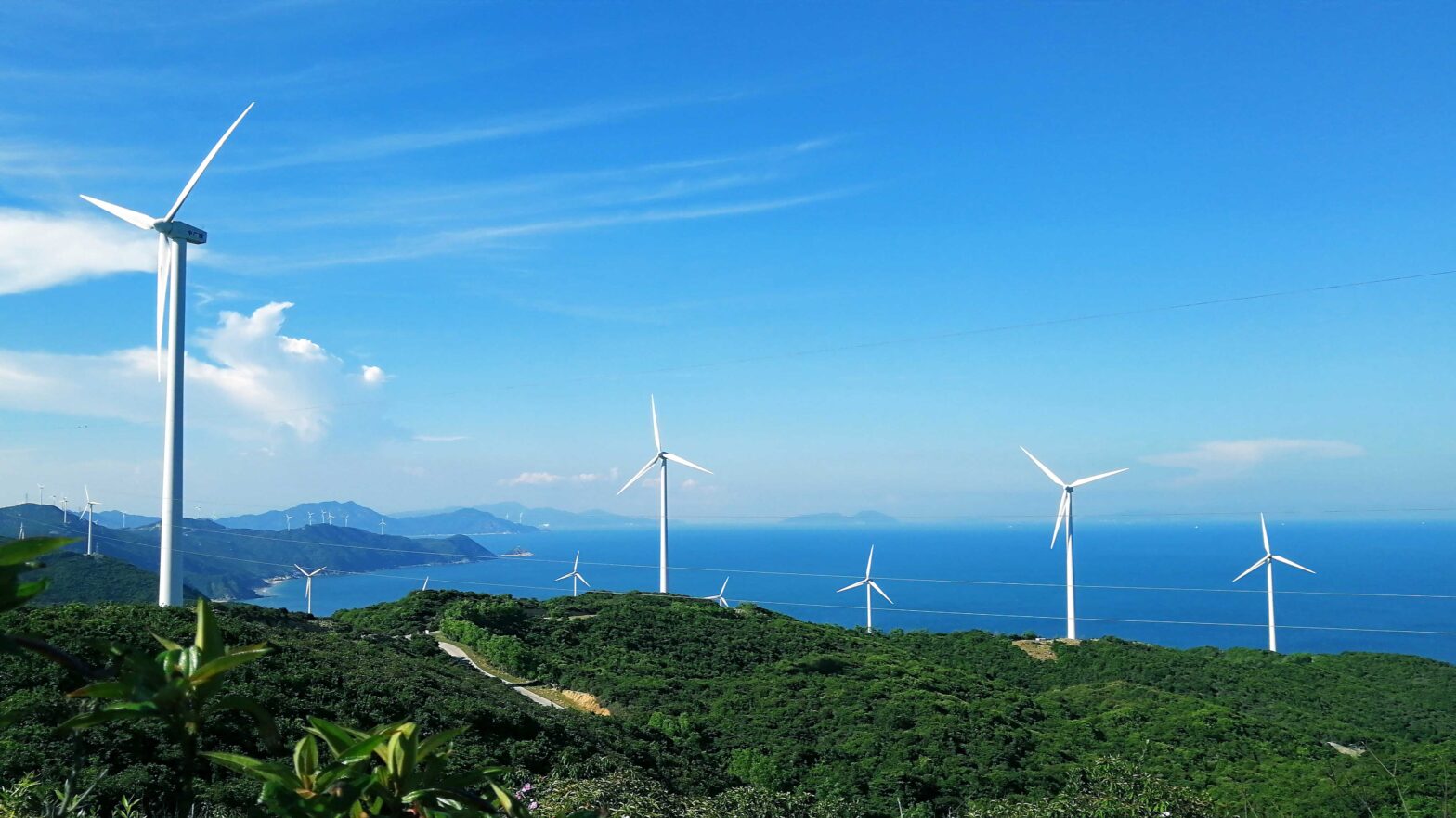 Wind turbines with mountains and ocean in the background