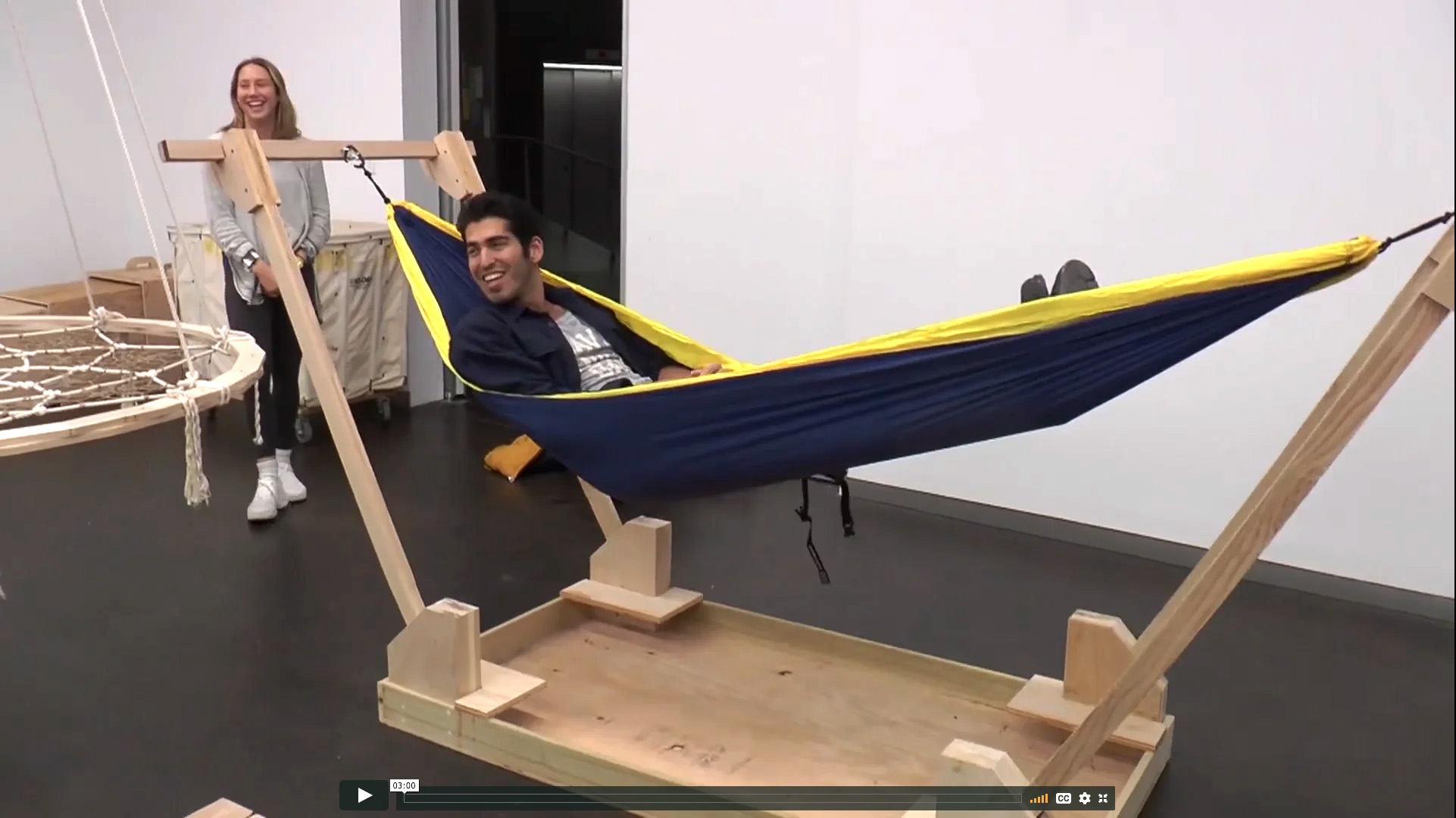 Student lies in hammock while classmate stands nearby