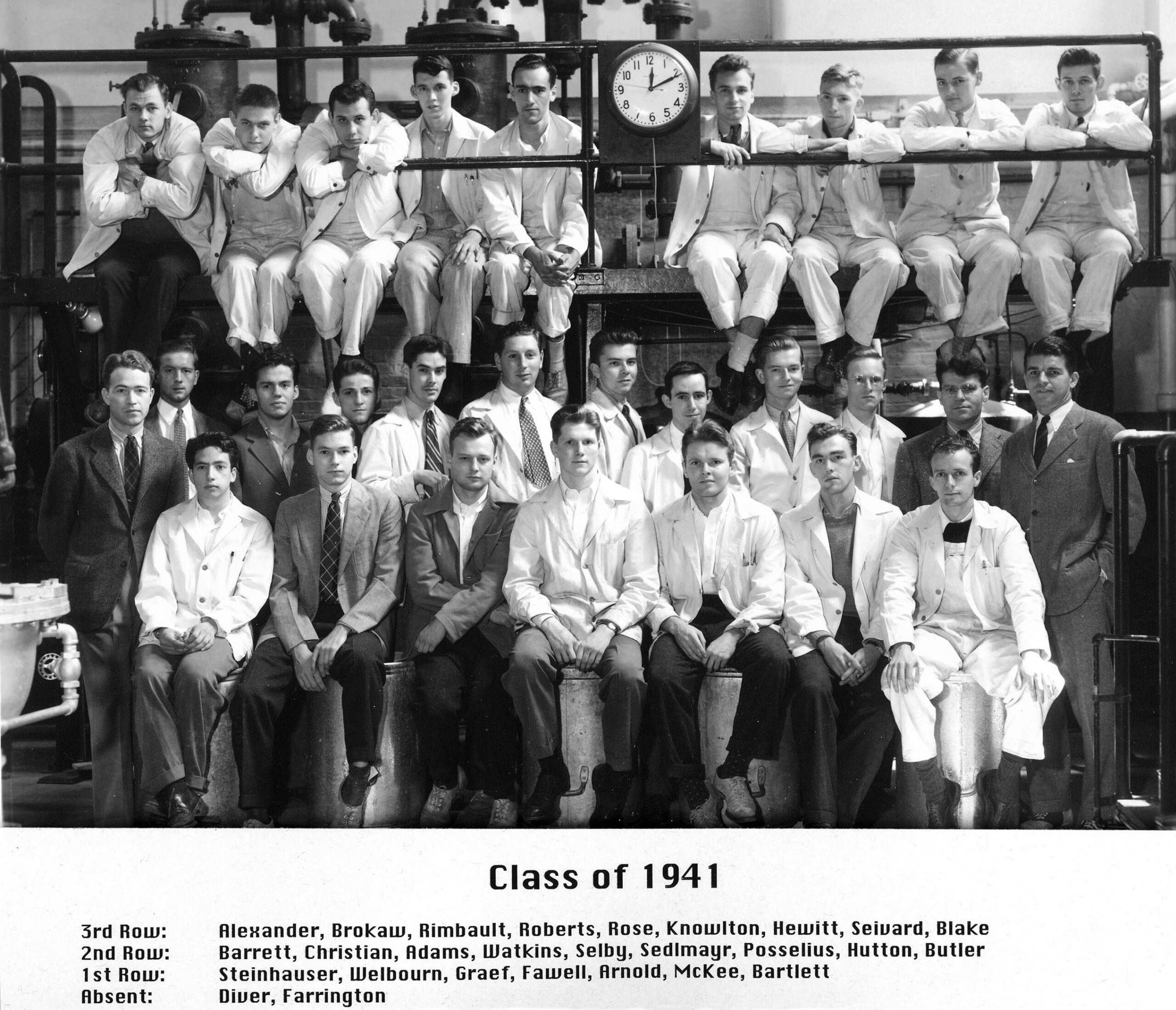 Older black and white photo of young men posing for class picture. The clock says 12:10 p.m.
