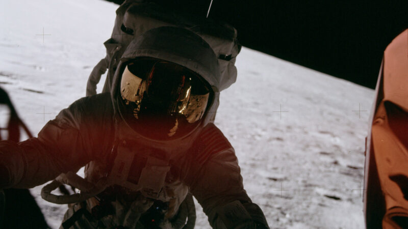 Astronaut descending the ladder onto the moon, staring at the camera, you can't see his face.
