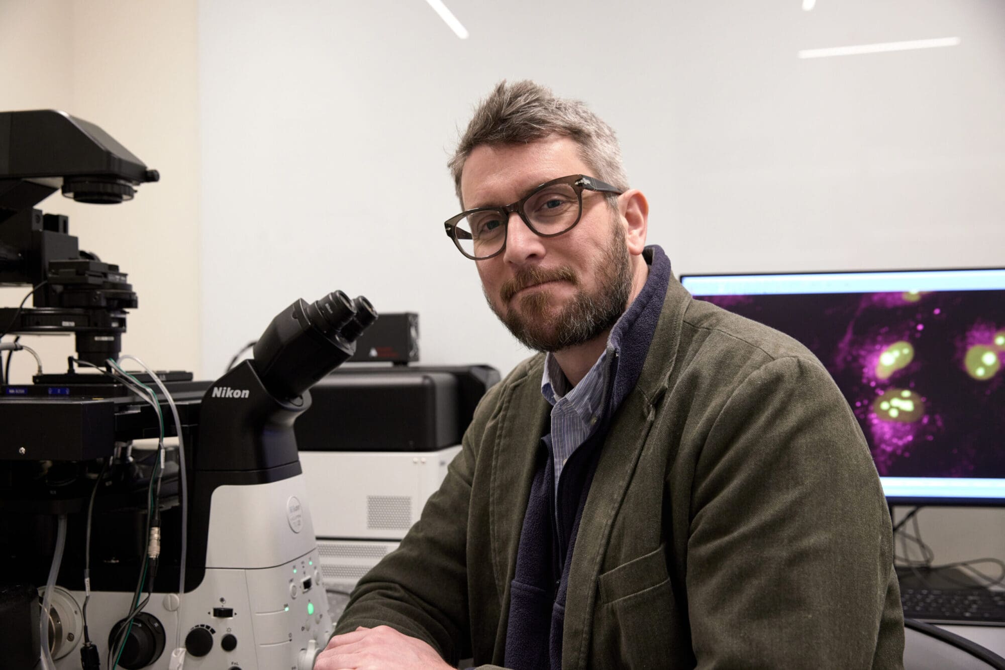 Clifford Brangwynne sits near a microscope in his lab