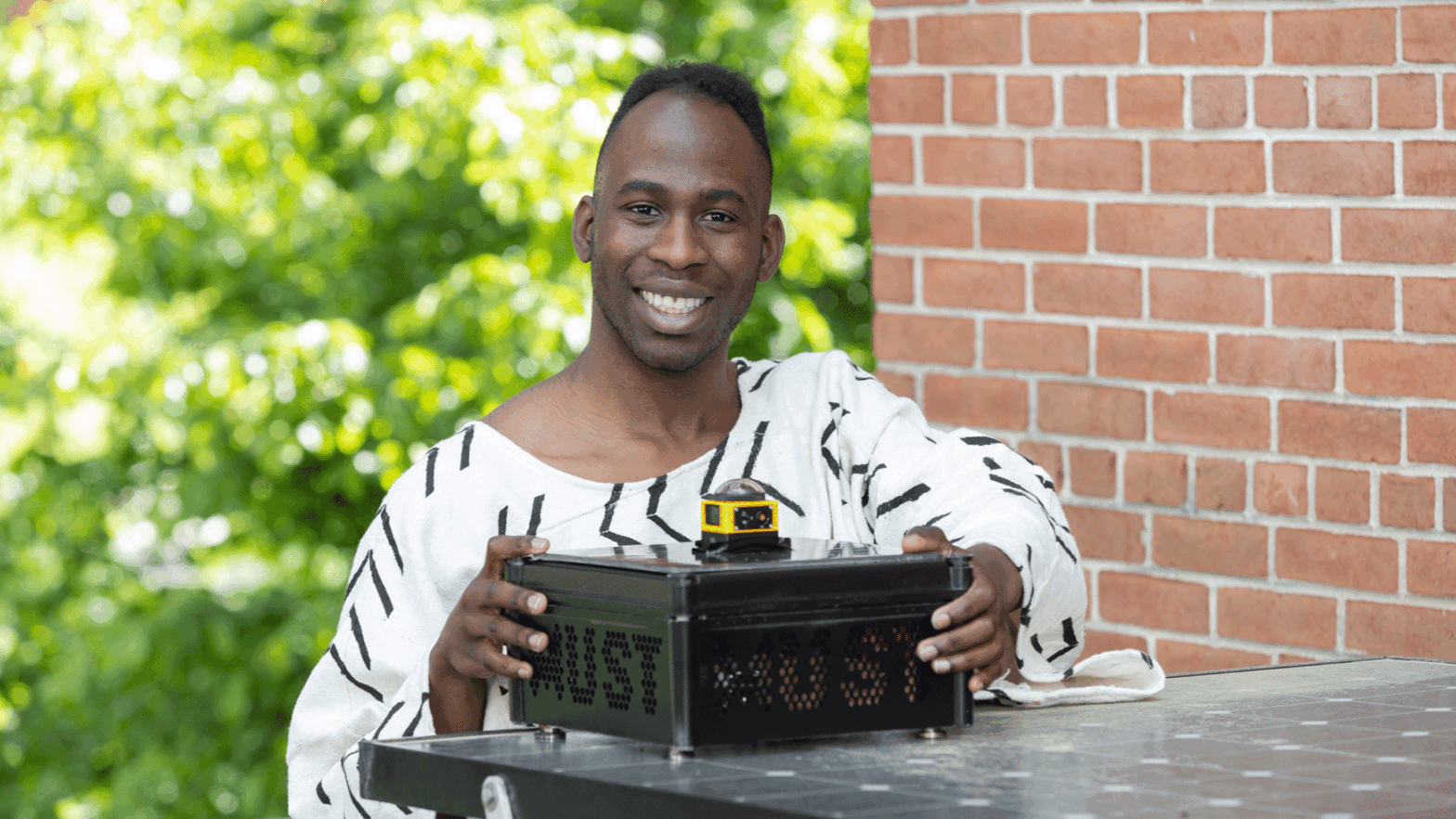 Jovan Aigbekaen holding a metal box containing air quality sensors used for his senior thesis research.