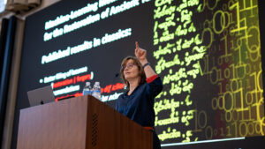 Speaker at podium with slide projected behind her showing ancient lettering and modern text.