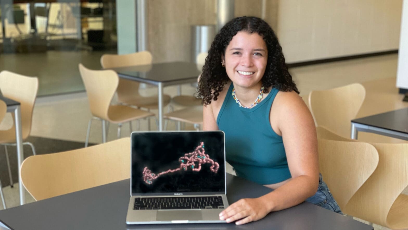 Student seated with laptop showing image of molecule.