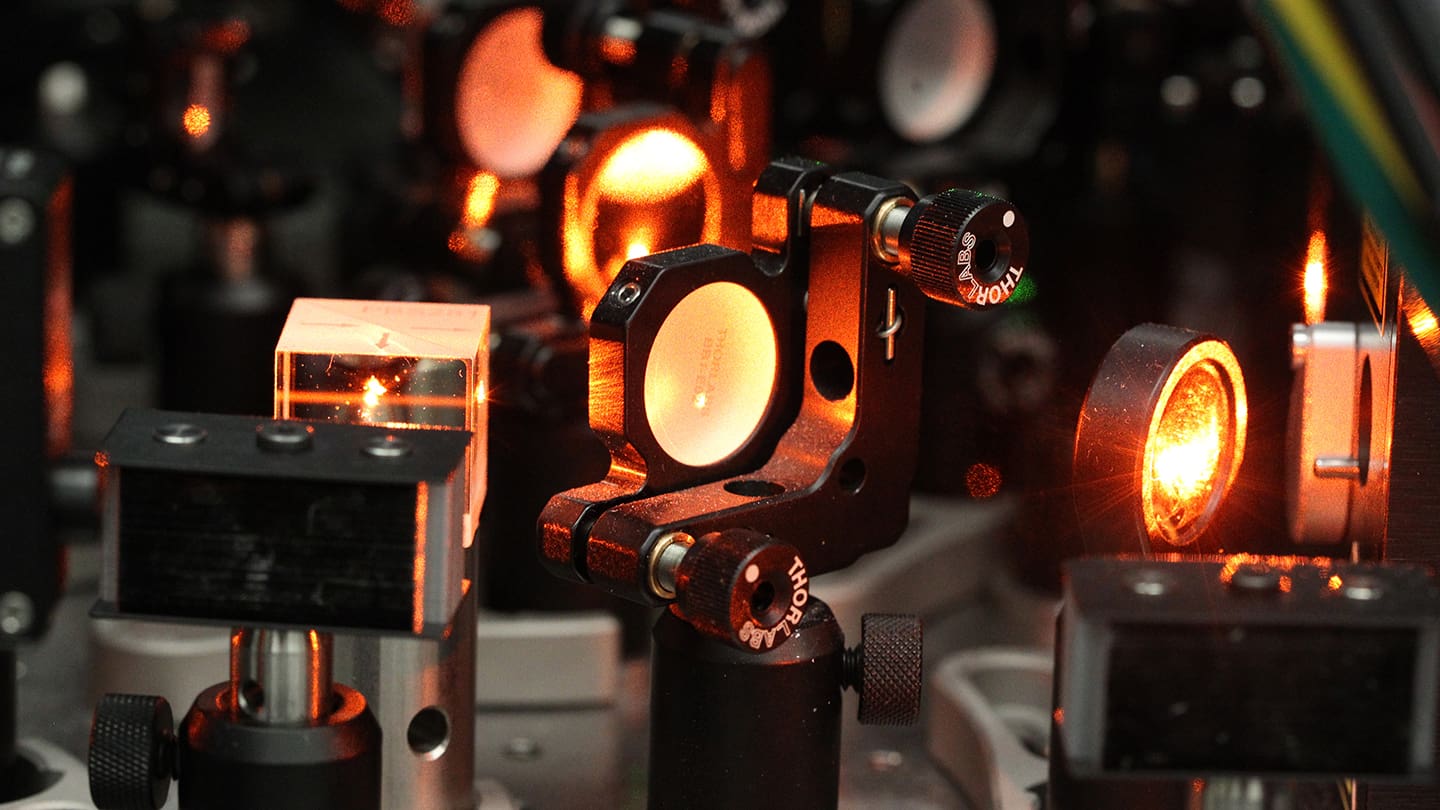 Orange light glows in a series of lenses inside a quantum computer.