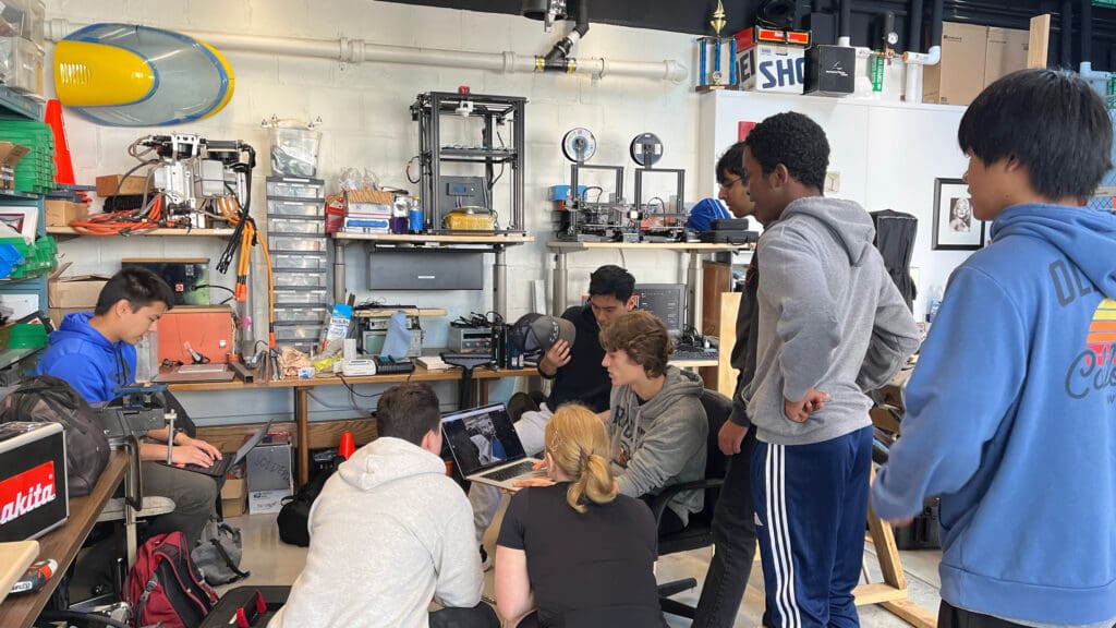 A group of students working on boat parts in a garage