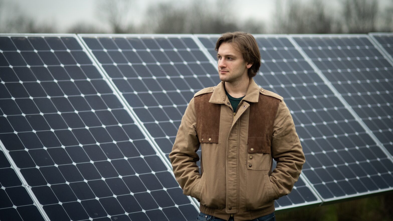A man stands in front of a solar panel array.