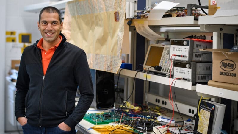 Verma posing in his lab with technical equipment.