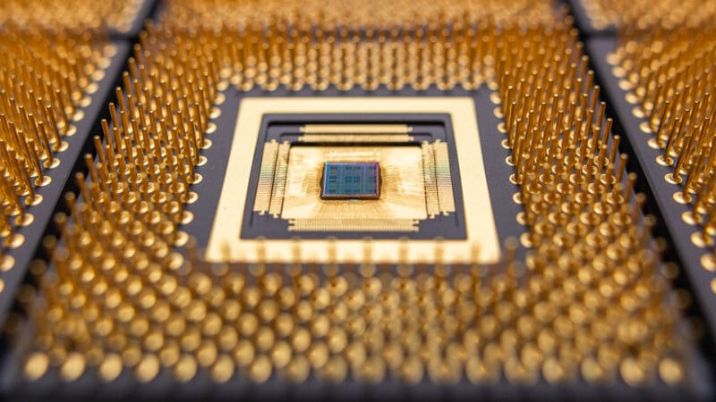 An advanced chip taped out surrounded by a gold square surrounded by a large array of gold pins.