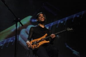 Stanley Jordan today, on stage, holding an electric guitar, and smiling.