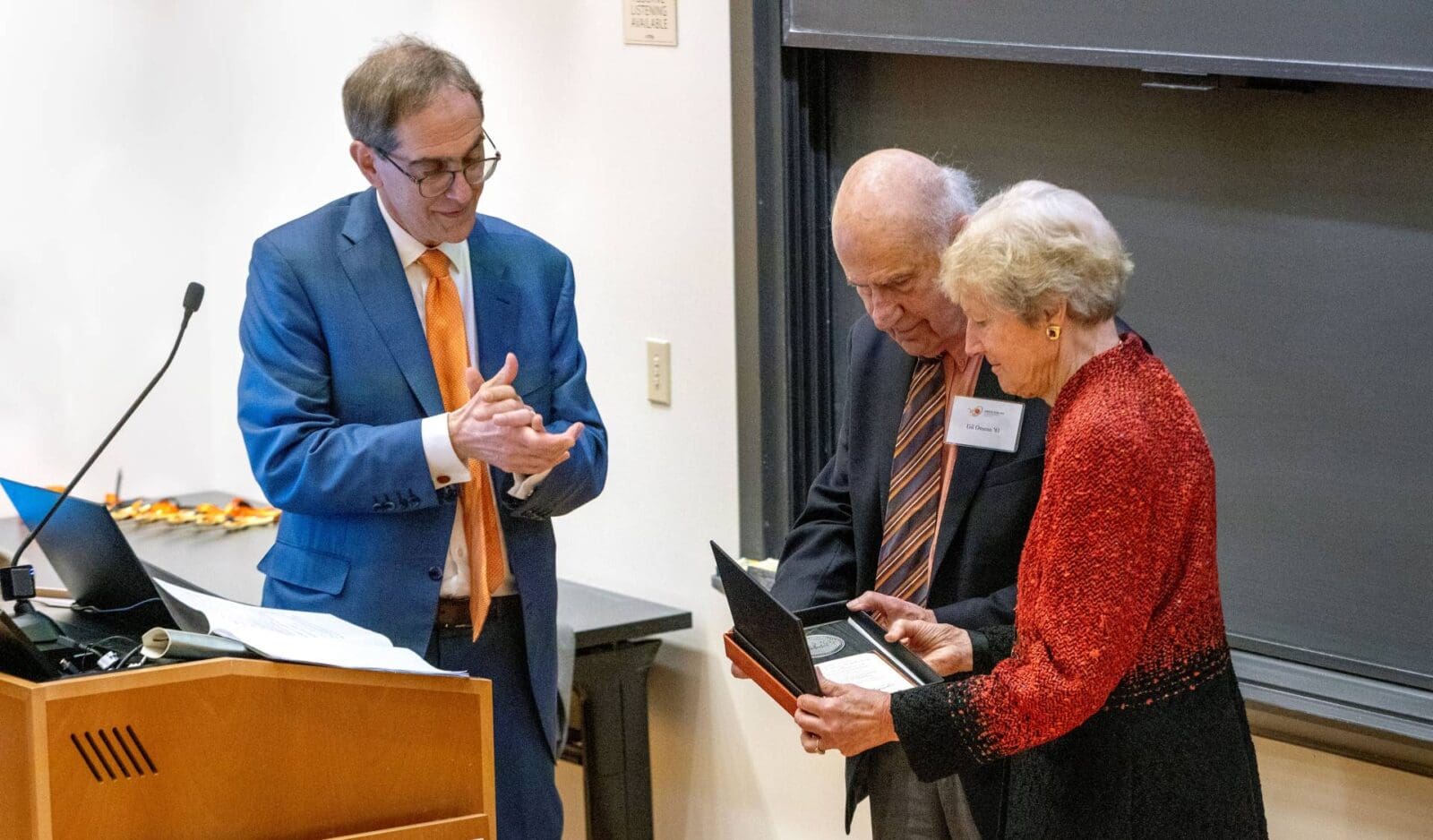 Christopher Eisgruber presents Gil Omenn and Martha Darling with a plaque