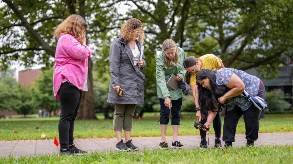 A group of woman use a heat sensor along a path