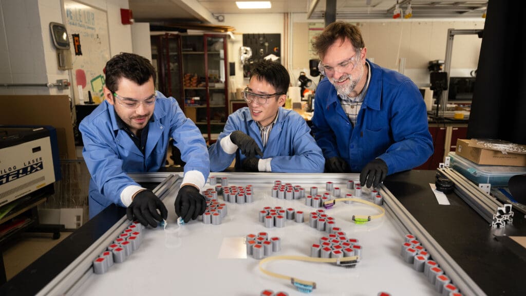 Three researchers position small robots on a table