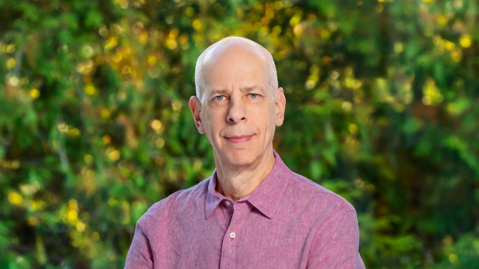 Man with white hair in a pink button-down shirt