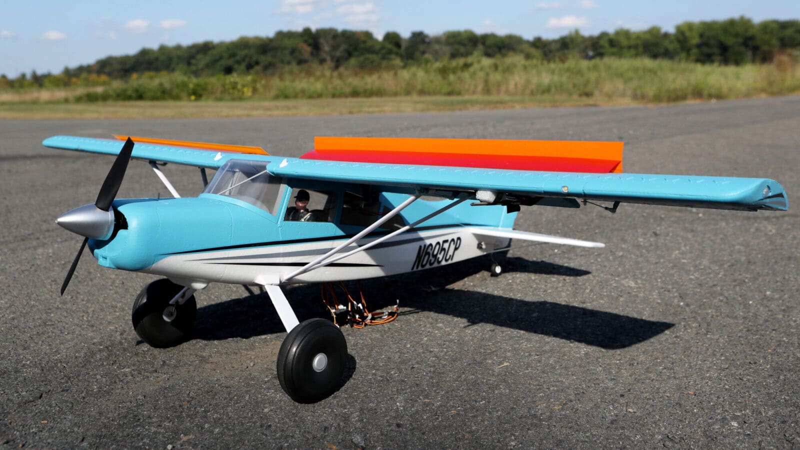 A model airplane with flaps raised sits on the runway