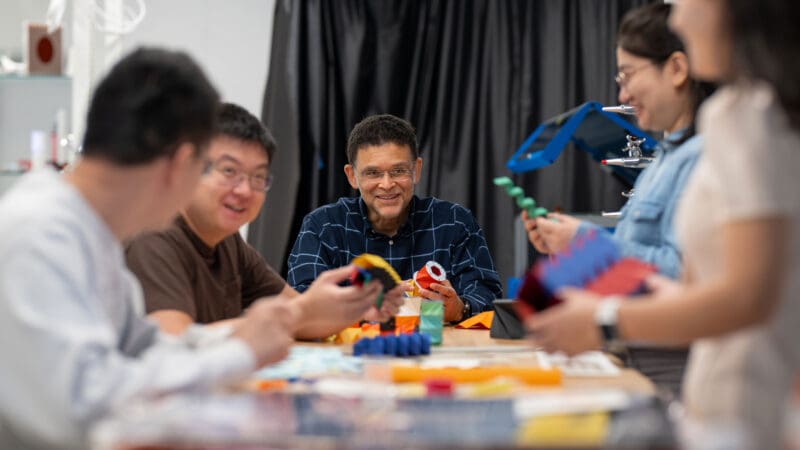 A group around a table holding cardboard figures folded in origami patterns