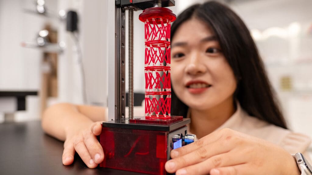 Woman working with a red, cylindrical structure made of plastic rods.