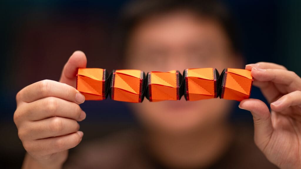 A cylindrical robot made of alternating black and orange segments.