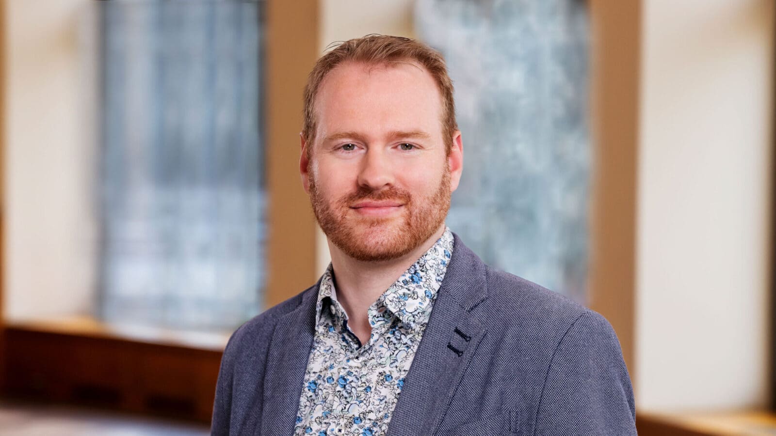 A man with a beard dressed in a blue shirt and jacket.