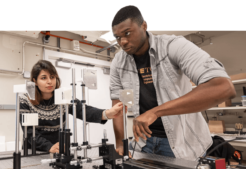 A woman and a man work at a laboratory bench with electronic equipment