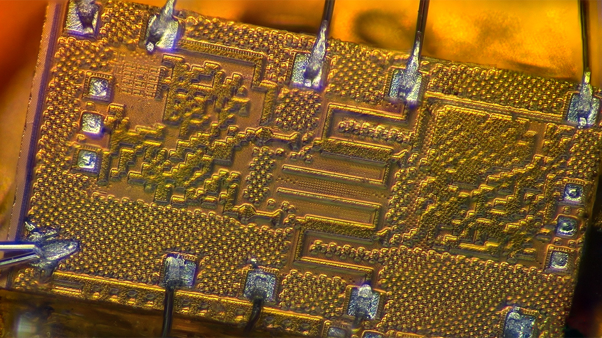 Closeup of gold-colored microchip showing circuitry patterns.