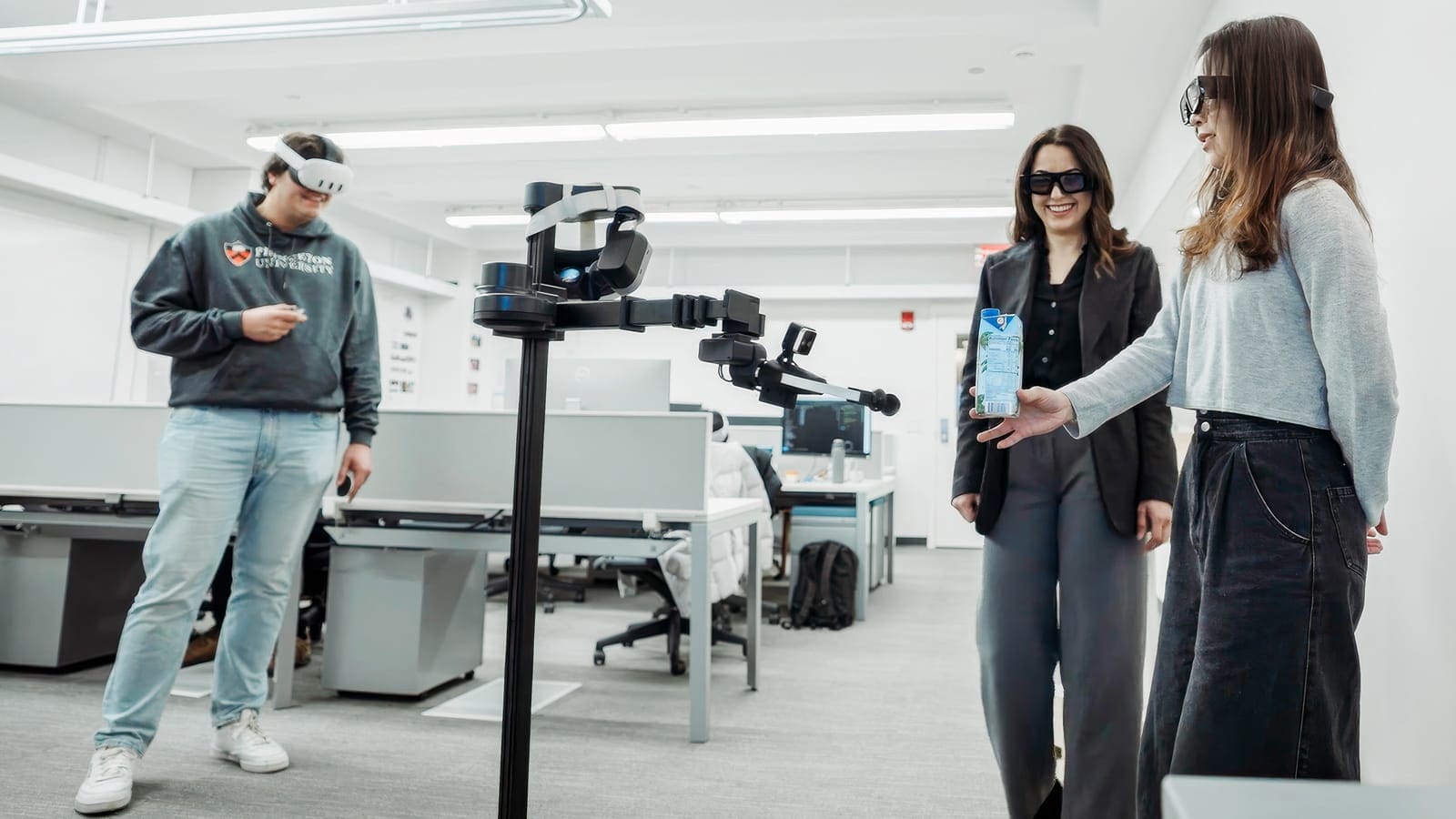 Three researchers wearing mixed reality headsets standing around a robot carrying a drink.