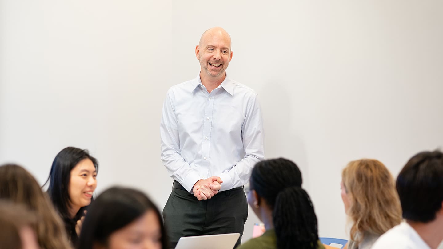 Charles Schroeder smiles broadly as he stands before a room of students.