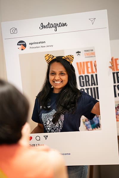 Student poses for photo inside a cut-out poster designed to look like an Instagram post.