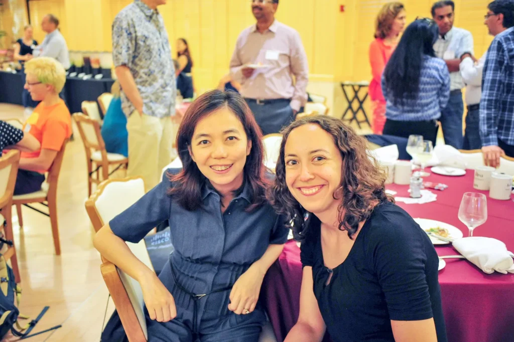 Fei-Fei Li and Olga Russakovsky sit at a table during an event.