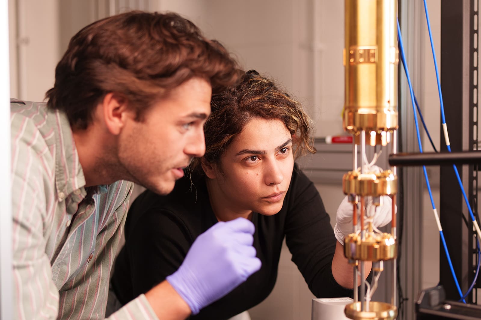 Two researchers study a detail on a quantum computing device.