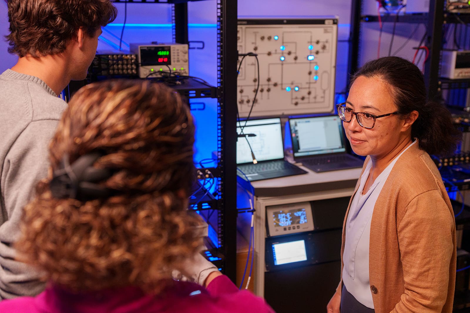 Nathalie de Leon speaks with two researchers in the lab.