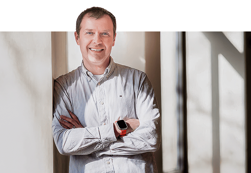 A man stands in a room with large windows
