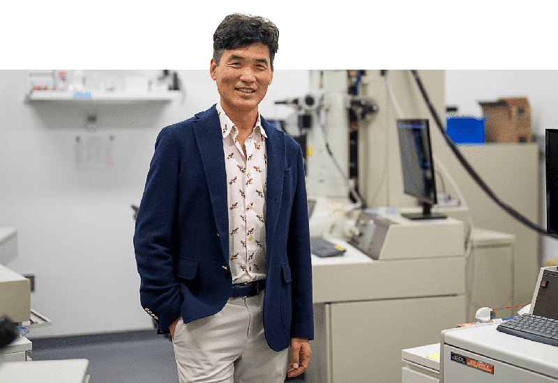 Sebastian Seung standing in front of lab equipment