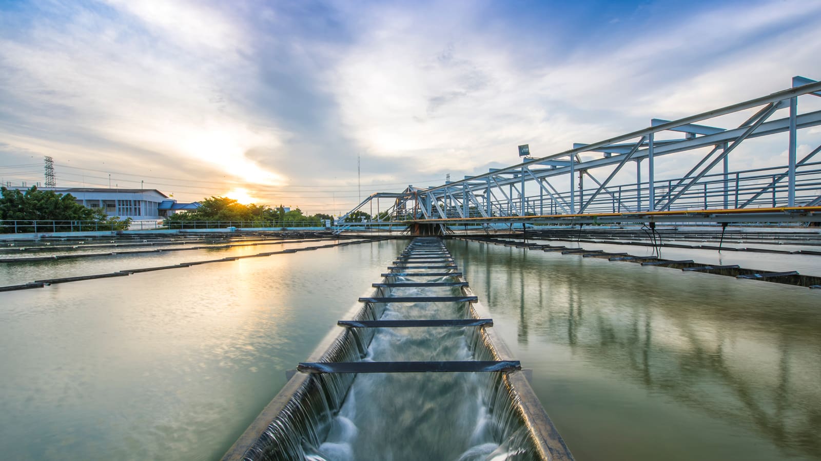 A structure of metal girders crossing a pond at a sewer plant